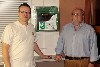 Klaus Dieter Kneisch (Erster Vorsitzender der Ottenauer Vereinsgemeinschaft) und Timo Hirth (DRK-Bereitschaftsleiter) bei der Inbetriebnahme des Defibrillators in der Merkurhalle. Foto: privat