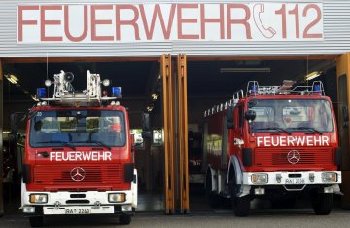 Auf dem Foto sieht man hochgezogene Garagentore des Rettungszentrums mit zwei Feuerwehrfahrzeugen.