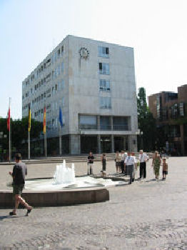 Das Bild zeigt das Rathaus von Gaggenau, im Vordergrund eine Personengruppe vor dem Brunnen.