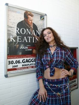 Julia Neigel steht an die Wand gelehnt vor dem Poster von Ronan Keating. 